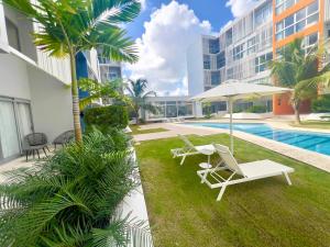 a patio with chairs and an umbrella and a pool at Downtown Chic Donde inicia la diversión en Punta Cana in Punta Cana
