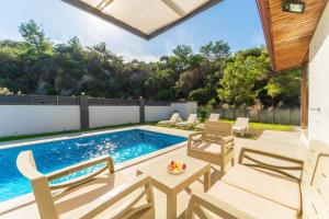 a patio with a pool and chairs and a table at Villa Albatros in Mergenli