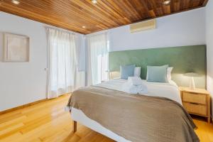 a bedroom with a large bed with a wooden ceiling at Casa da Colina, By Home Match in Sesimbra +55 photos