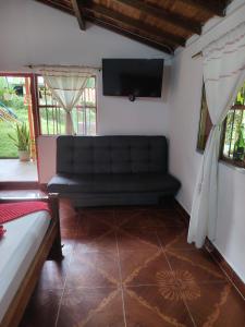 a living room with a couch and a flat screen tv at Libélula finca-hotel in Concepción