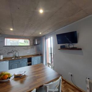a kitchen with a wooden table and a television on the wall at Casas do Pargo - Casa B Palheiro in Ponta do Pargo +14 photos