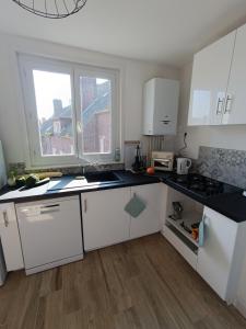 a kitchen with white cabinets and black counter tops at Le Refuge de la Tour in Calais
