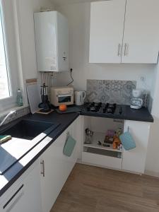 a kitchen with white cabinets and a stove top oven at Le Refuge de la Tour in Calais