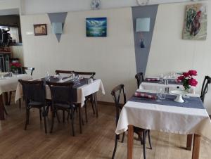 a dining room with white tables and chairs and flowers at Le Kalblin in Fréland