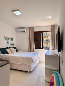 a white bedroom with a bed and a television at Flat Ilhéus Olivença pé na areia no Condomínio Jubiaba in Ilhéus