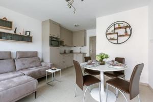 a living room with a couch and a table and chairs at Casiola - Spacious & light apartment with double terrace in Nieuwpoort