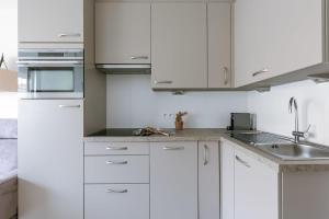 a white kitchen with white cabinets and a sink at Casiola - Spacious & light apartment with double terrace in Nieuwpoort