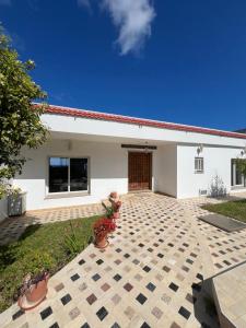a white house with a brick patio in front of it at Villa Horizon & Pool Bizerte in Bizerte
