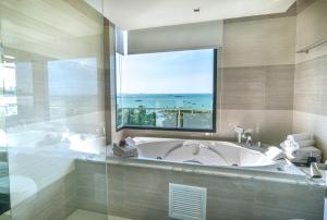 ein Badezimmer mit Badewanne und großem Fenster in der Unterkunft Mera Mare Pattaya in Pattaya