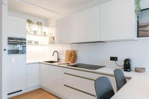 a white kitchen with white cabinets and a sink at Casiola - Nice apartment close to the beach with parking in Nieuwpoort