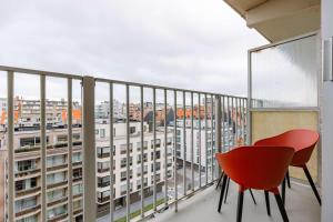 a red chair and a table on a balcony at Casiola - Nice apartment close to the beach with parking in Nieuwpoort