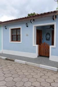 a blue house with a door and a porch at Suítes da Sereia in Cananéia +7 photos