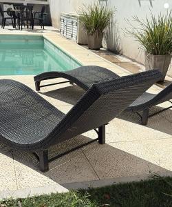 a black wicker bench next to a swimming pool at Monoambiente centrico-Paseo Plaza in Navarro