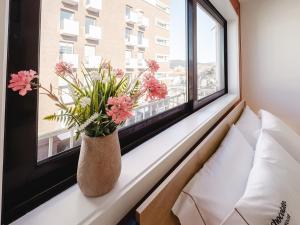 a vase with pink flowers sitting on a window sill at Chocolate House in Viana do Castelo