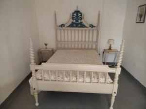 a white bed in a room with two tables at Casa dos Josés in Elvas