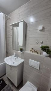 a white bathroom with a sink and a mirror at Apartman Dreams Lukavica in Lukavica +15 photos