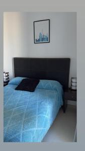 a bedroom with a bed with a blue comforter at Departamento 3 ambientes-Paseo Plaza in Navarro