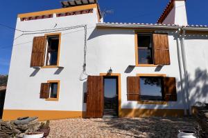 a white house with wooden doors and windows at Casa da Vinagra in Pé da Serra