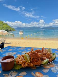 a plate of food on a table next to the beach at Suíte dos Reis in Angra dos Reis