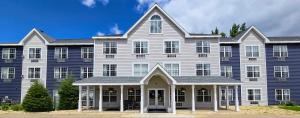 a large house with a large blue building at GrandStay Hotel & Suites Hastings in Hastings