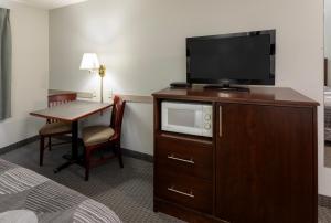 a hotel room with a television on a dresser with a table at GrandStay Hotel & Suites Hastings in Hastings