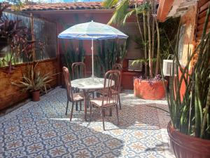 a table with chairs and an umbrella on a patio at Casa estilo colonial próximo Paço Municipal in Goiânia
