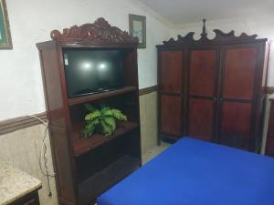 a living room with a tv and a cabinet at Casa estilo colonial próximo Paço Municipal in Goiânia