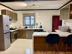 a kitchen with stainless steel appliances and blue chairs at The Calm Corner in Trevallyn