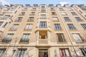 a tall tan building with windows and a balcony at Saint mandé Place du marché in Saint-Mandé