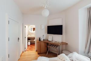 a white room with a desk and a bedroom at Hotel Château Palacio in Fauvillers