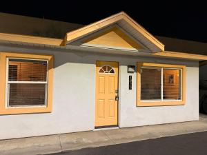 a house with a yellow door and two windows at Golden Sol Casita in Tempe