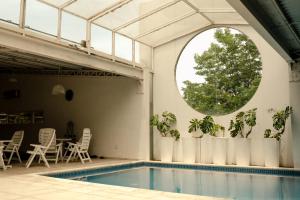 a pool in a building with a window and plants at Locanda Hotel in Novo Hamburgo +101 photos