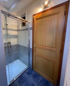 a bathroom with a shower and a wooden door at Chambre avec piscine, saison estivale in Urrugne