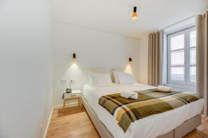 a white bedroom with a large bed and a window at Correio Velho Hotel in Lisbon