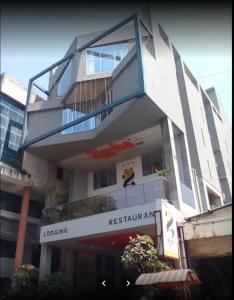 un edificio alto y blanco con un letrero de restaurante en el frente en Hotel Zorba Inn, en Kolhapur