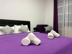 a purple bed with two rolled towels on it at Restoran,,Vuk,, Tršić in TrÅ¡iÄ‡