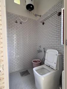 a bathroom with a white toilet and a shower at R's Bolli Kudike in Madikeri