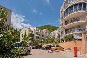 a parking lot with cars parked in front of a building at Petrovac Pearl Apartment in Petrovac na Moru