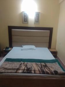 a bed in a bedroom with a white mattress and a light at Royal Park Residential Hotel in Chittagong