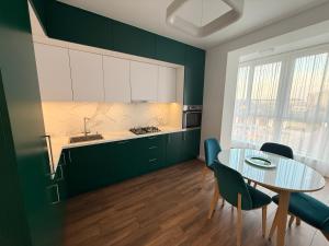 a kitchen with green cabinets and a table and chairs at GS Green Apartment in Starokostyantyniv