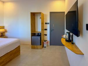 a hotel room with a bed and a desk with a television at Hiraya Guesthouse in Ukulhas