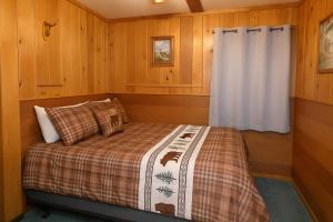 a small bedroom with a bed in a wooden room at Old Stoney's Walleye- Pet Friendly in Arbor Vitae