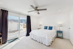 a white bedroom with a bed and a large window at Library House in Durango