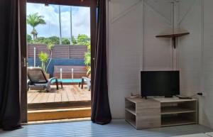 a living room with a tv and a sliding glass door at Location saisonnière in Petit-Bourg