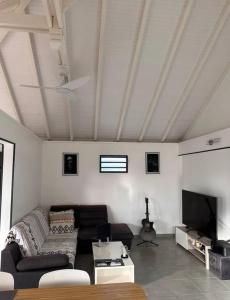 a living room with a couch and a flat screen tv at Location saisonnière in Petit-Bourg +5 photos