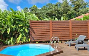 a backyard with a swimming pool and a wooden fence at Location saisonnière in Petit-Bourg