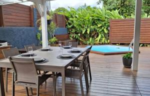a table and chairs on a patio with a pool at Location saisonnière in Petit-Bourg