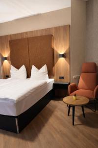 a hotel room with a bed and a chair at Hotel und Restaurant Hohe Schule in Herborn