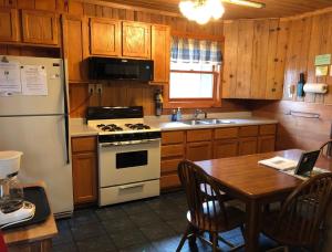 a kitchen with a white stove and a table and a refrigerator at Old Stoney's Walleye- Pet Friendly in Arbor Vitae