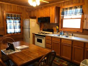 a kitchen with a table and a refrigerator and a sink at Old Stoney's Walleye- Pet Friendly in Arbor Vitae